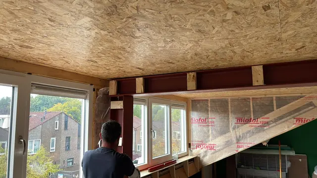 Vakman van GOGU Totaalbouw bij de nieuwe ramen van een dakopbouw met isolatie en stalen balken