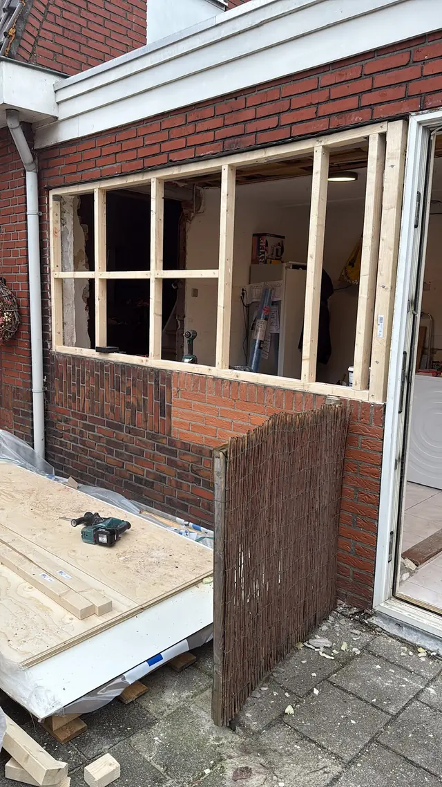 Nieuw houten regelwerk in een opening van een bakstenen gevel