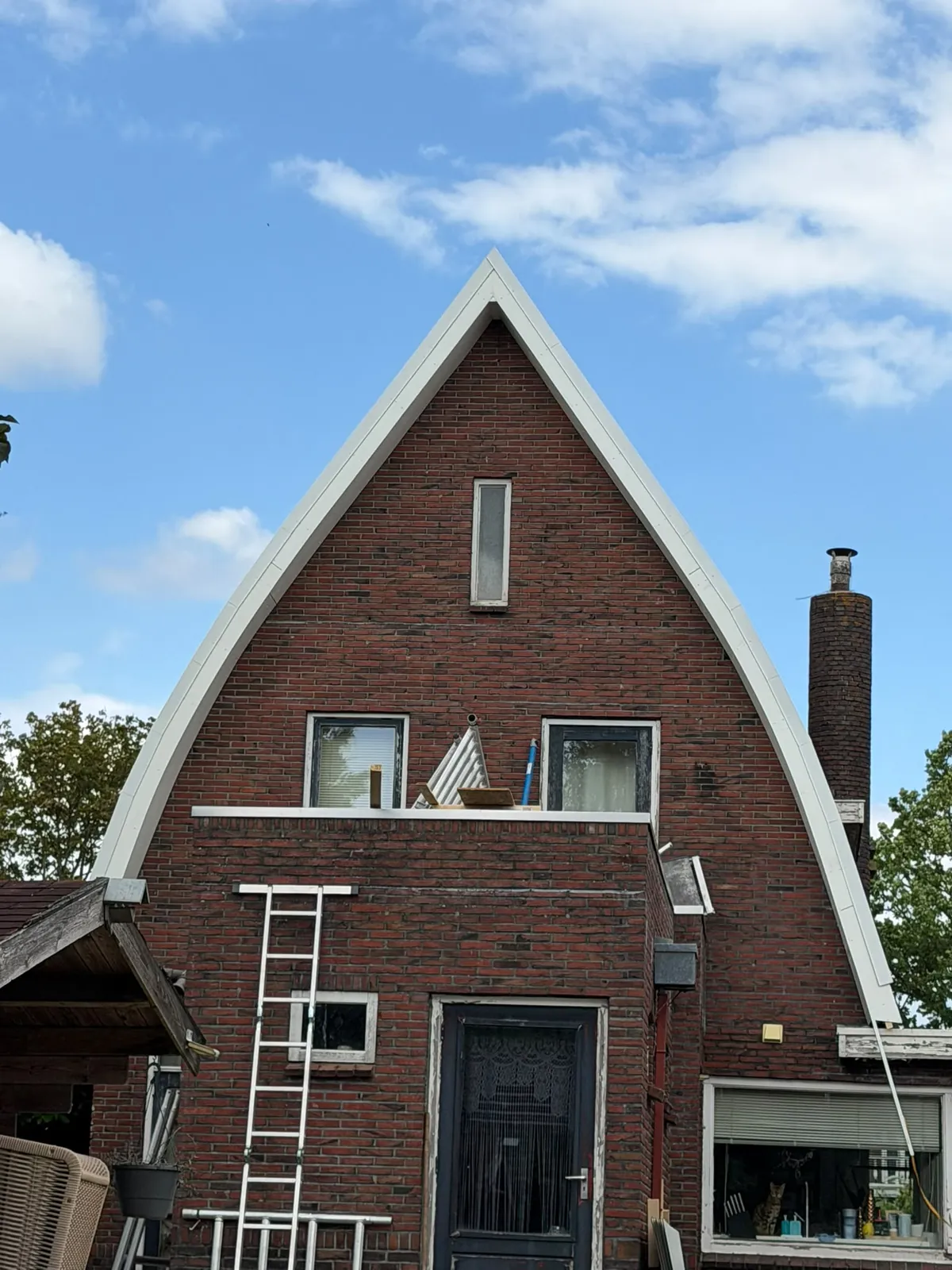 Woning met puntgevel tijdens onderhoud aan de houten overstekken