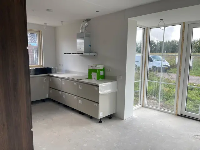 Nieuwe keukenkasten in een lichte ruimte met grote glazen deuren naar buiten