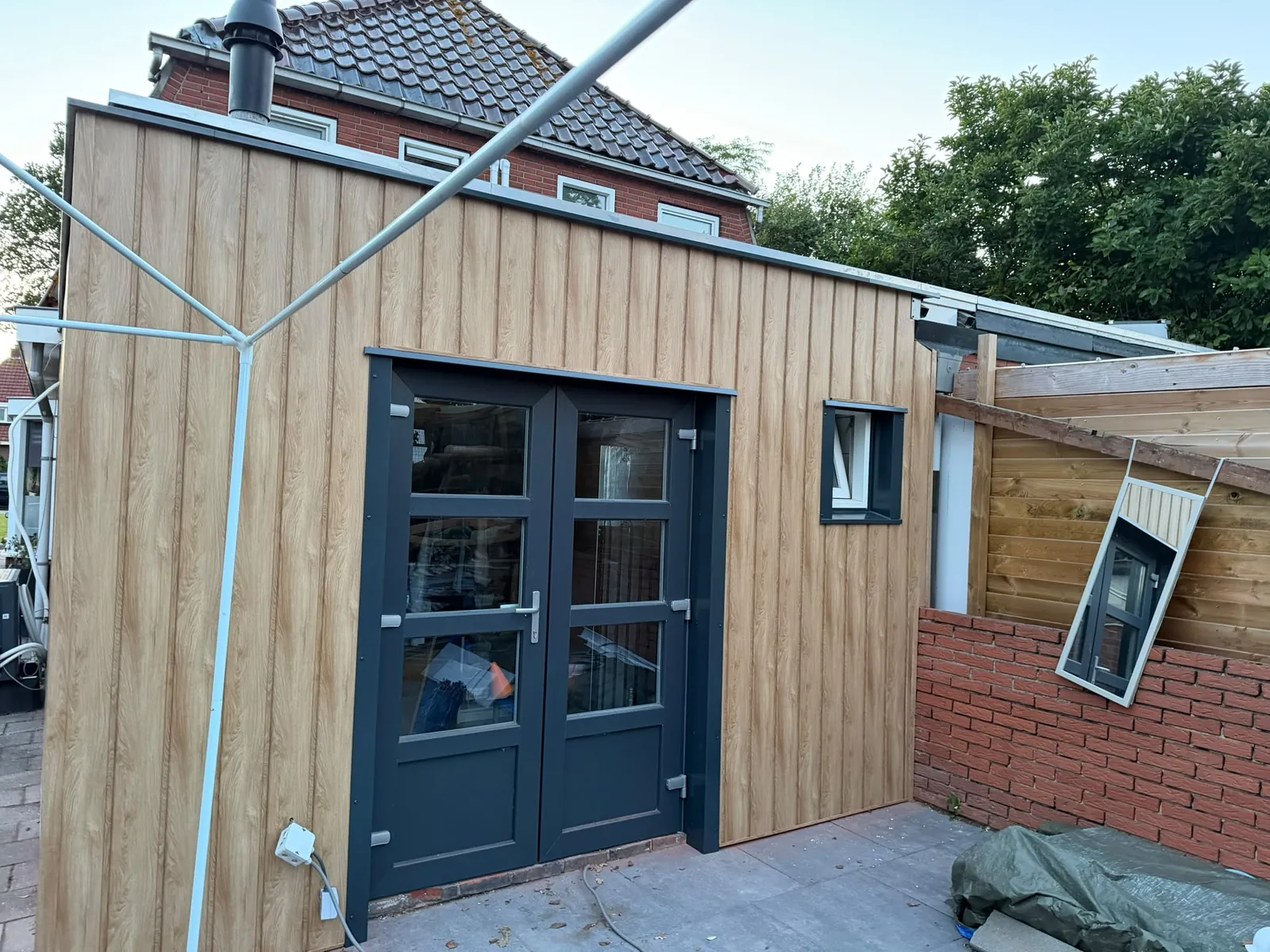 Afgeronde uitbouw met houten gevelbekleding en dubbele tuindeuren